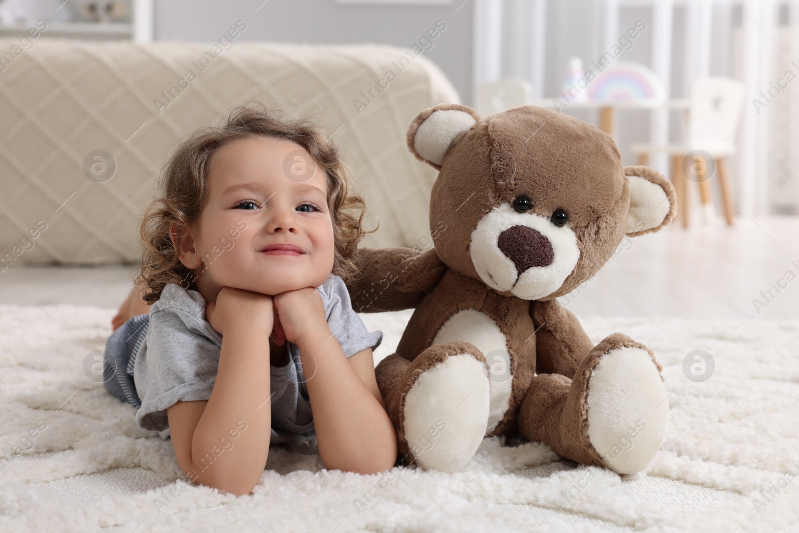 Photo of Cute little girl with teddy bear on floor at home