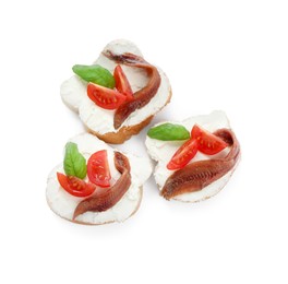 Photo of Delicious sandwiches with cream cheese, anchovies, tomatoes and basil on white background, top view