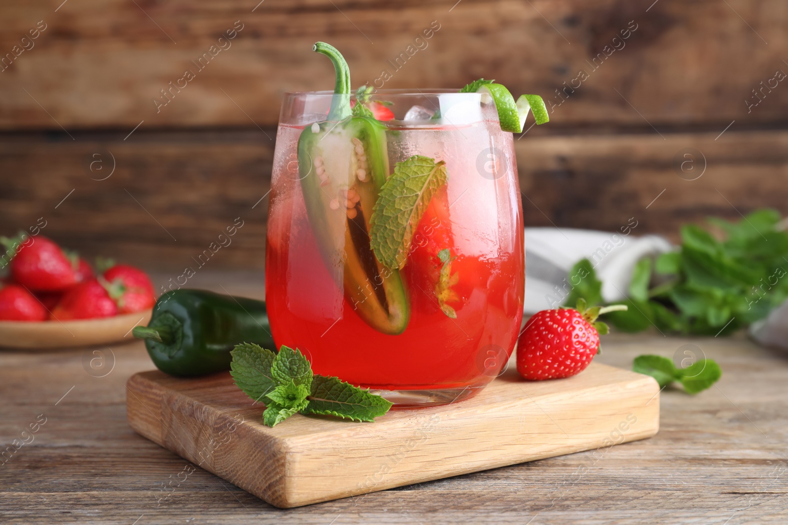 Photo of Spicy strawberry cocktail with jalapeno and mint on wooden table