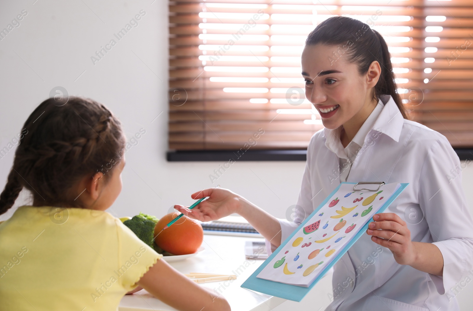 Photo of Little girl visiting professional nutritionist in office