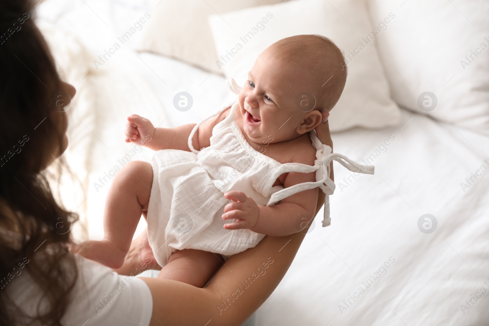 Photo of Happy young mother with her cute baby on bed at home