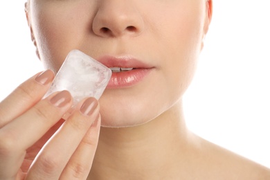 Young woman with ice cube on white background, closeup. Skin care