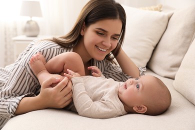 Photo of Young woman with her little baby on sofa at home