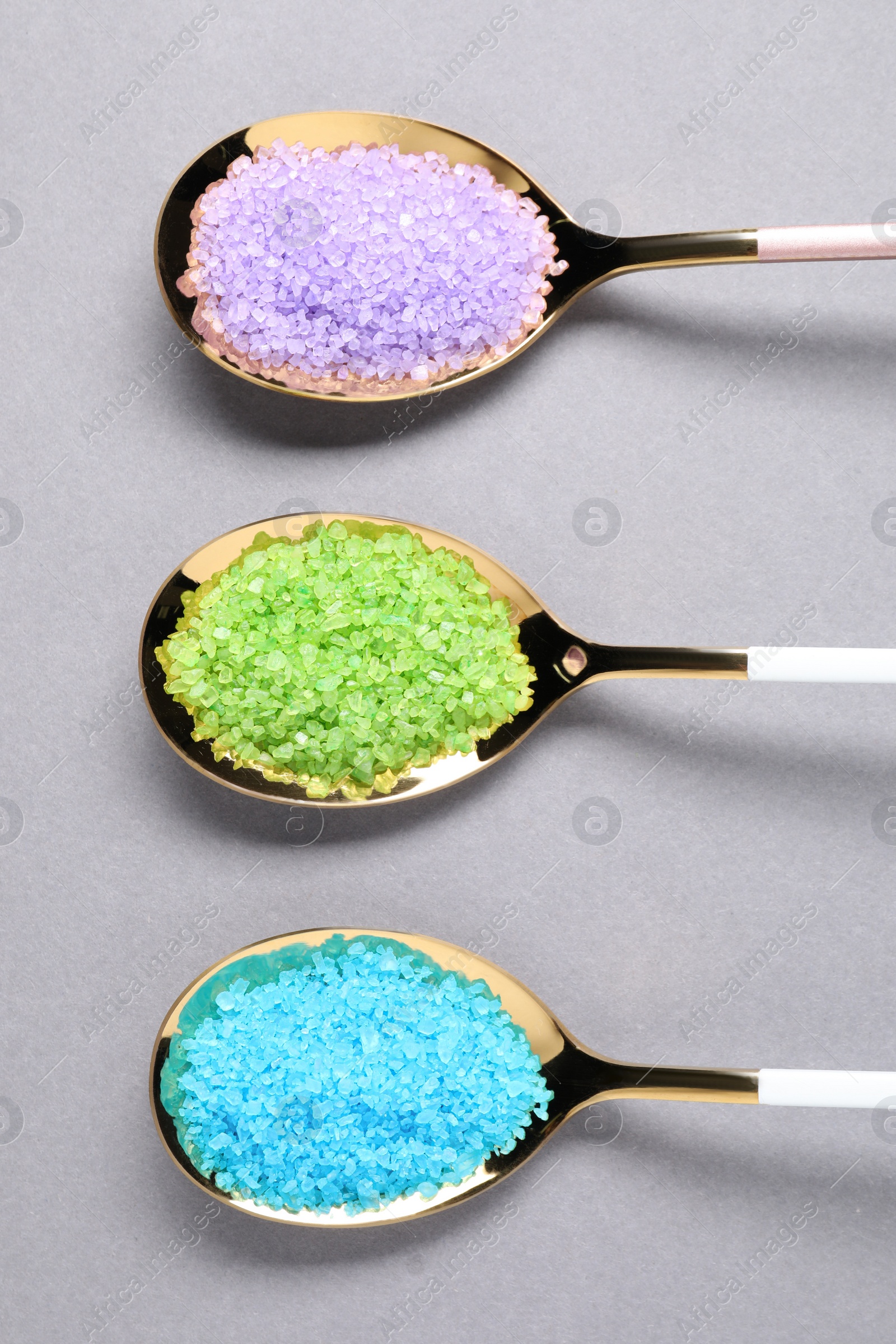 Photo of Spoons with colorful sea salt on light grey table, flat lay