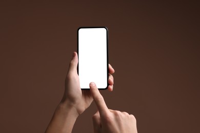 Photo of Man using smartphone with blank screen on brown background, closeup. Mockup for design