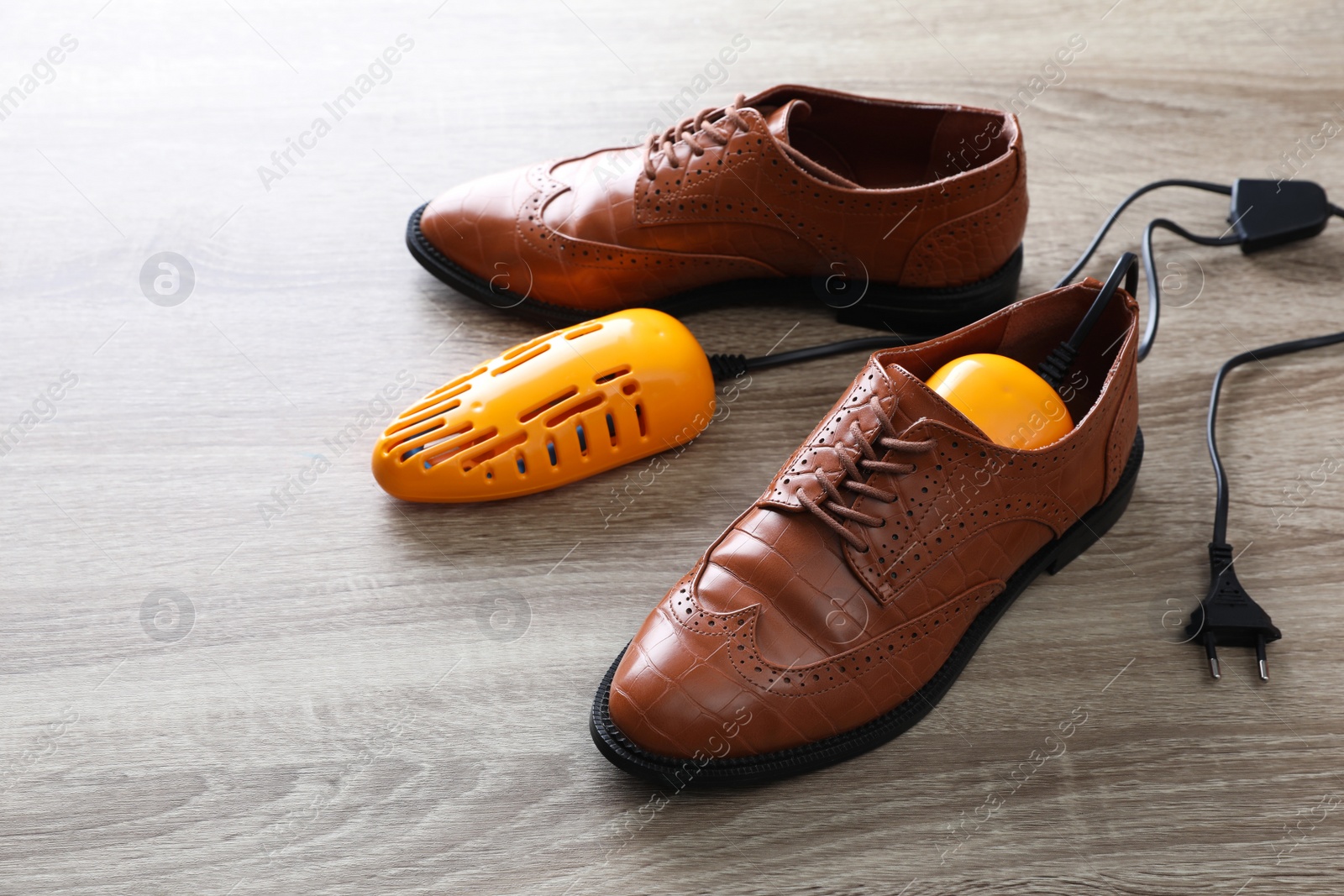 Photo of Pair of stylish shoes with modern electric footwear dryer on wooden background. Space for text