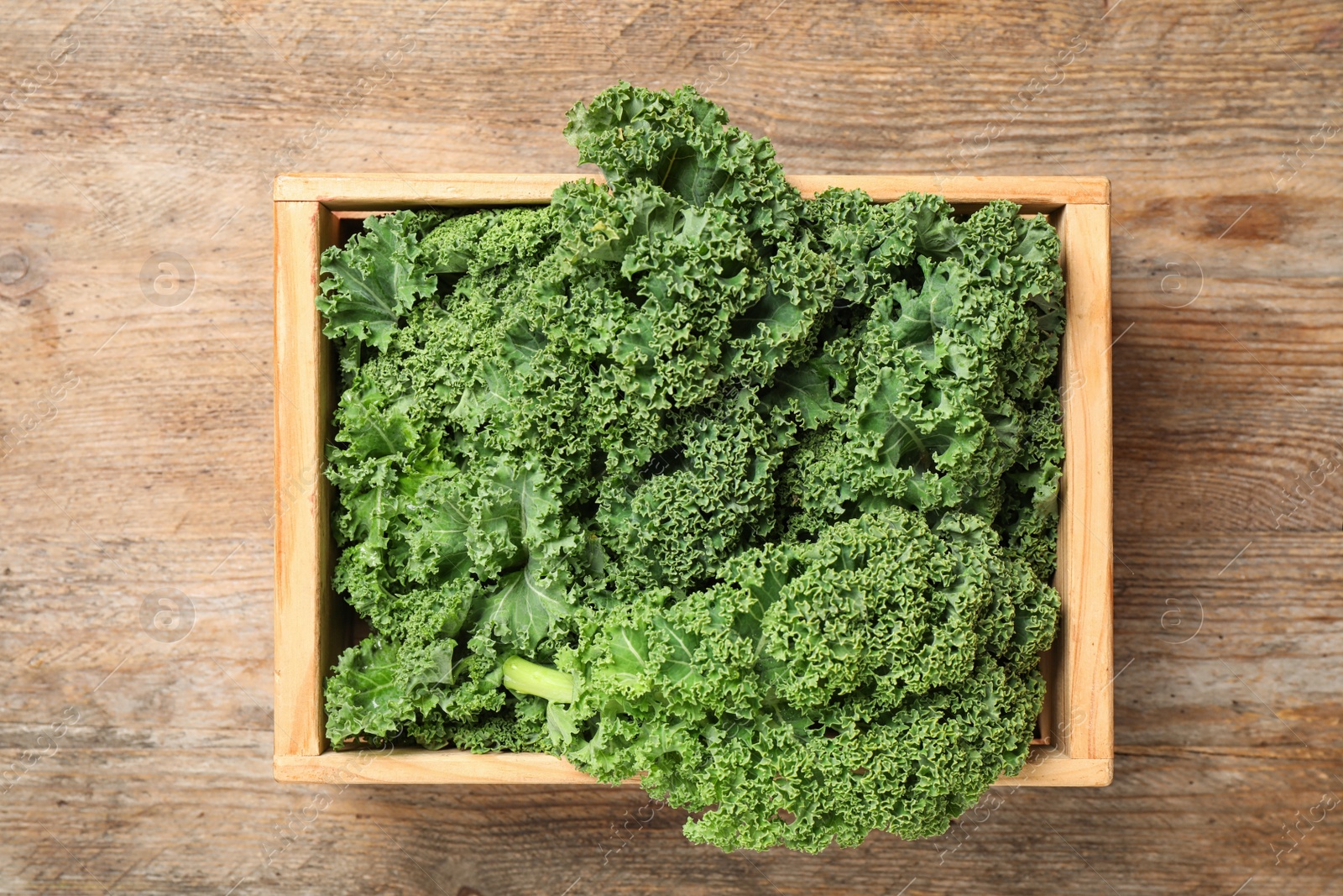 Photo of Fresh kale leaves on wooden table, top view