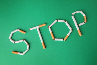 Photo of Word Stop made of broken cigarettes on green background, flat lay. Stop smoking concept