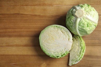 Photo of Whole and sliced cabbages on wooden table