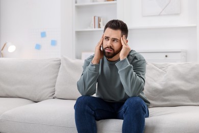 Man suffering from headache on sofa at home