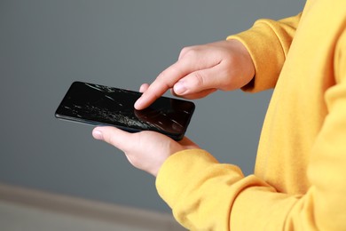 Photo of Man holding damaged smartphone on light grey background, closeup. Device repairing