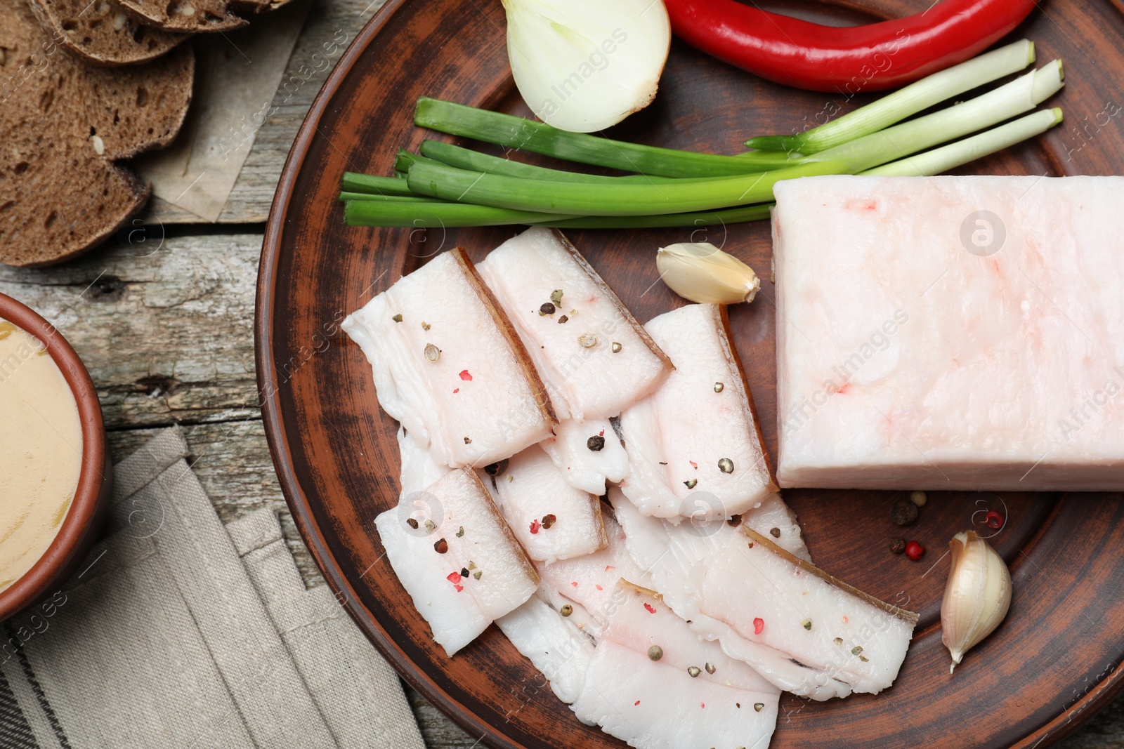 Photo of Tasty salt pork with vegetables served on wooden table, flat lay