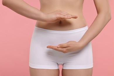 Woman holding something on pink background, closeup. Women's health