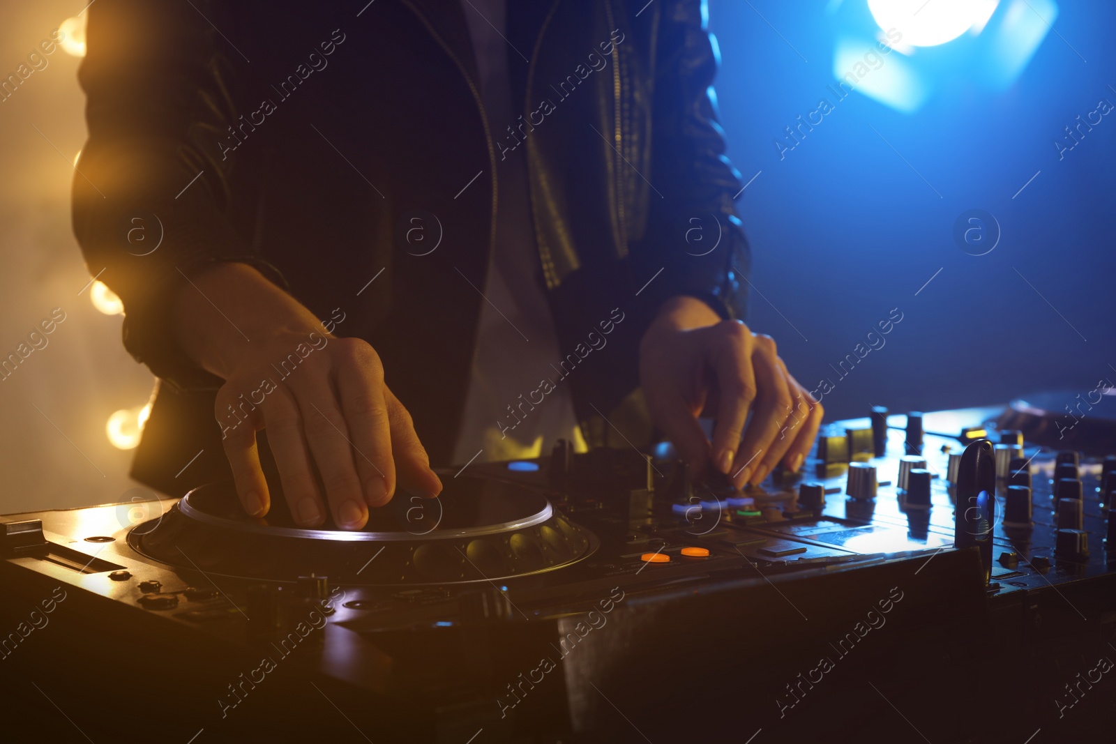 Photo of DJ creating music on modern console mixer in night club, closeup