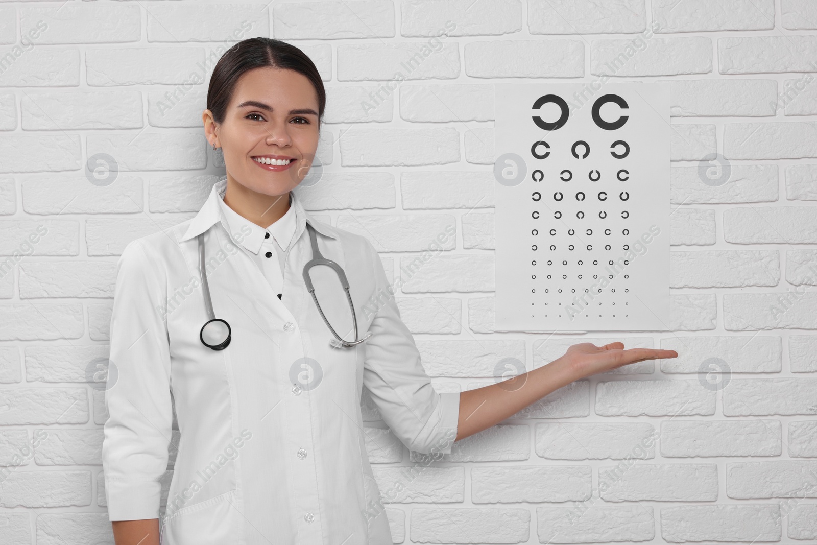 Photo of Ophthalmologist showing vision test chart on white brick wall