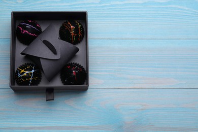 Photo of Box of tasty chocolate candies on light blue wooden table, top view. Space for text