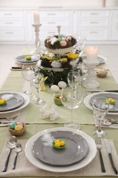 Beautiful Easter table setting with burning candles indoors