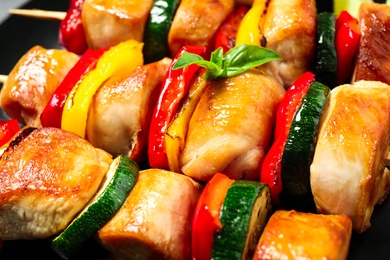 Photo of Delicious chicken shish kebabs with vegetables on plate, closeup