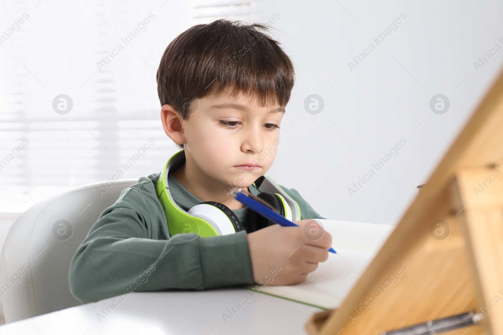 Photo of Cute little boy with modern tablet studying online at home. E-learning