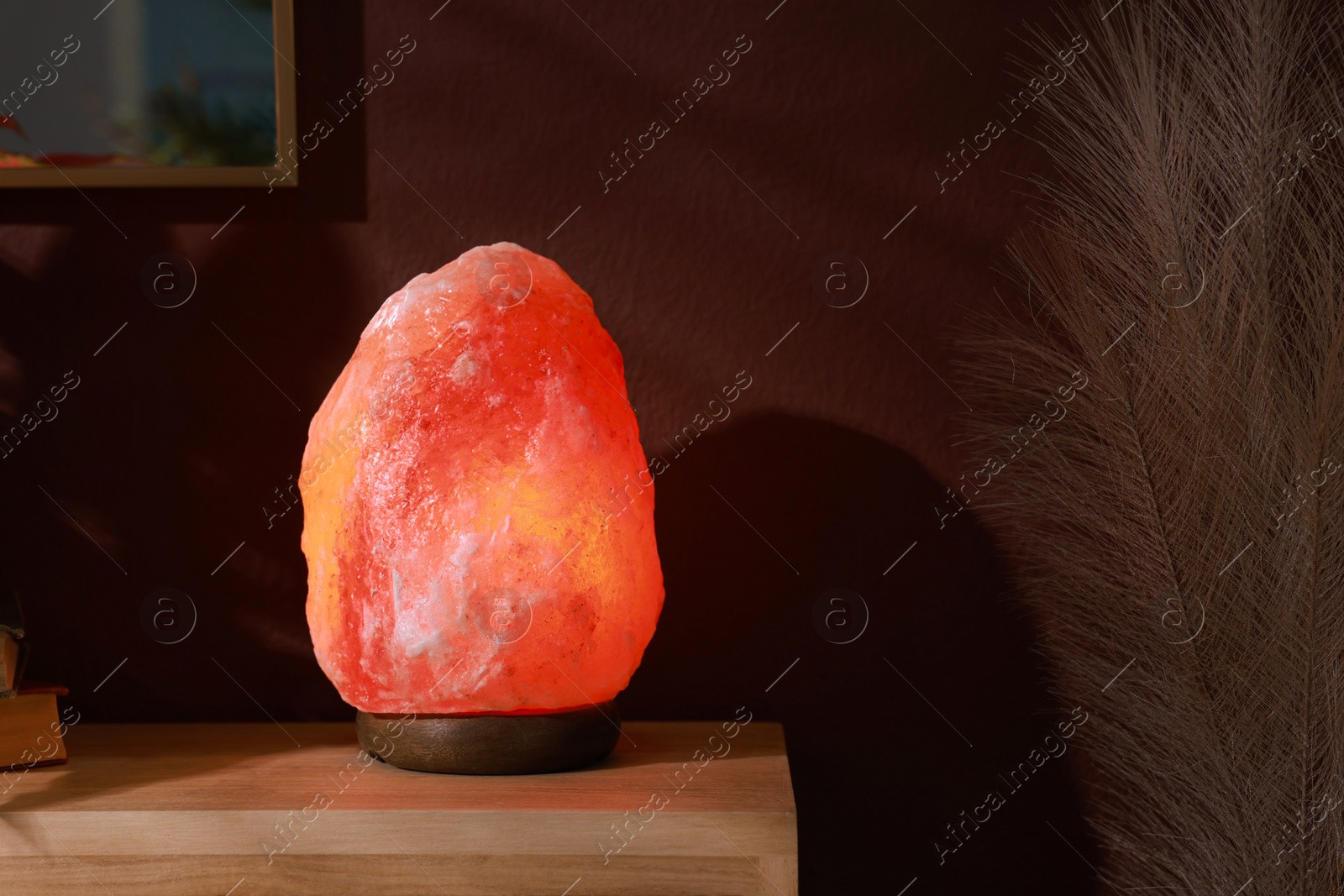 Photo of Himalayan salt lamp on wooden table near brown wall indoors