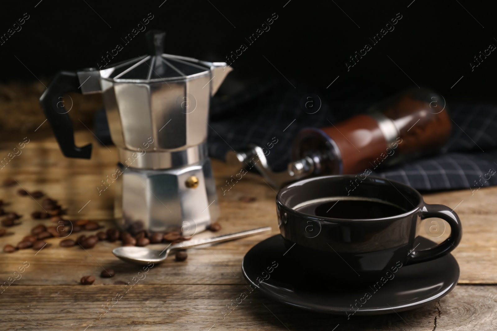 Photo of Cup of aromatic coffee, moka pot and scattered beans on wooden table. Space for text