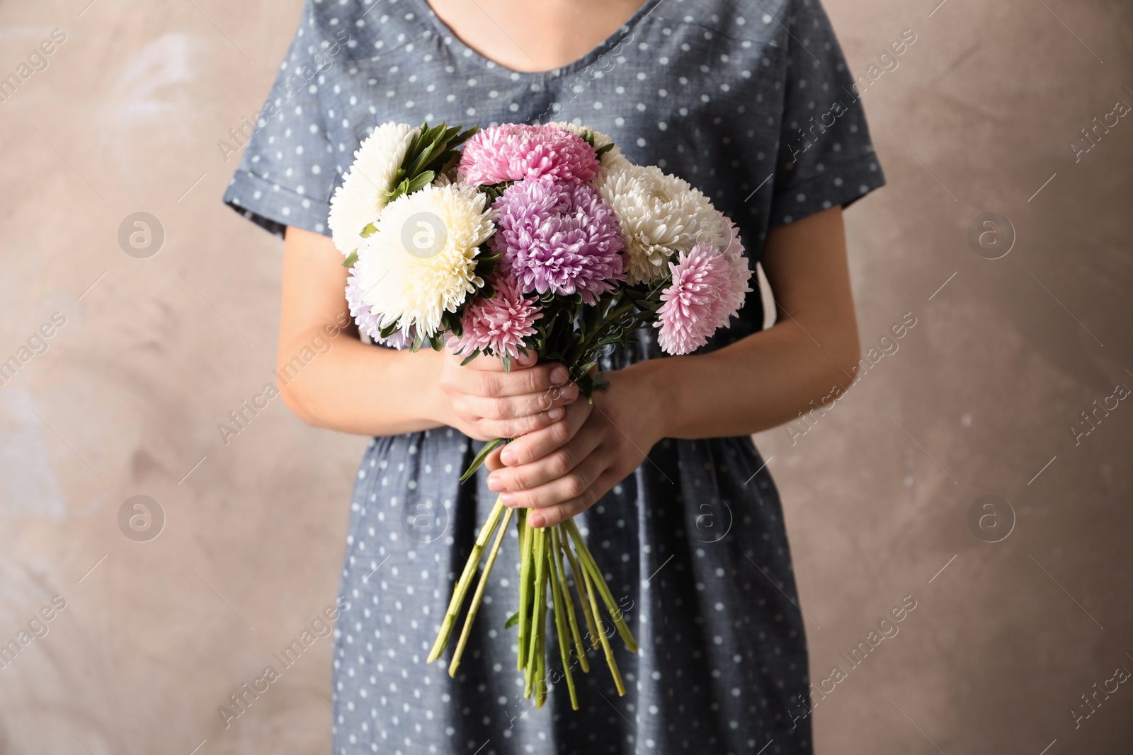 Photo of Woman holding beautiful aster flower bouquet against color background