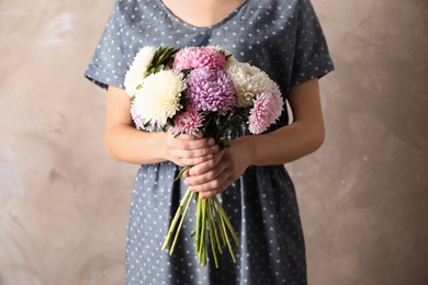 Woman holding beautiful aster flower bouquet against color background