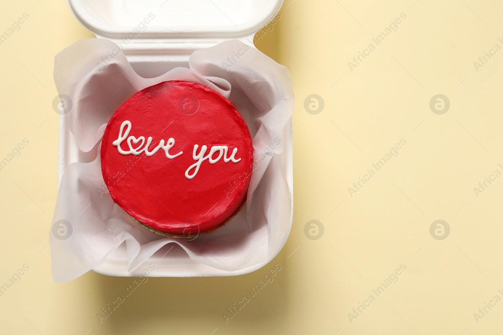 Photo of Bento cake with Love You text in takeaway box on beige table, top view. Space for text. St. Valentine's day surprise