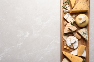 Photo of Different delicious cheeses served on grey table, top view. Space for text