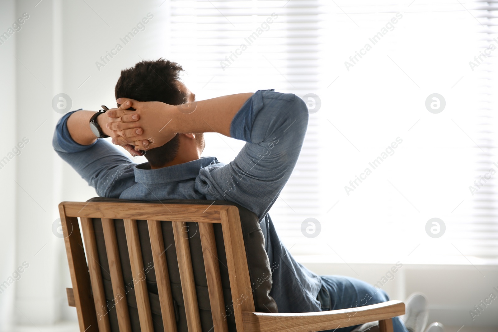 Photo of Young man relaxing in armchair near window at home