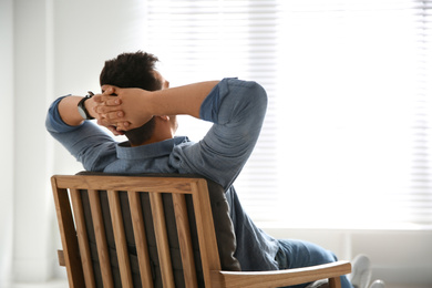 Young man relaxing in armchair near window at home