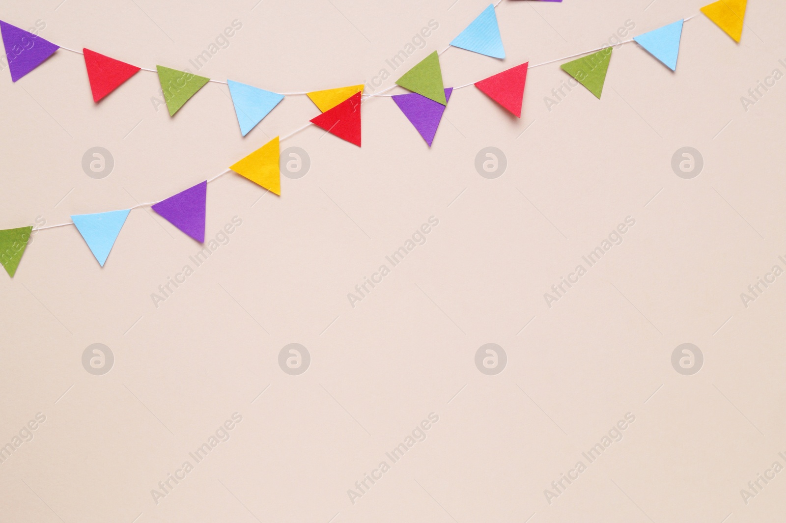 Photo of Colorful bunting flags on beige background, flat lay. Space for text