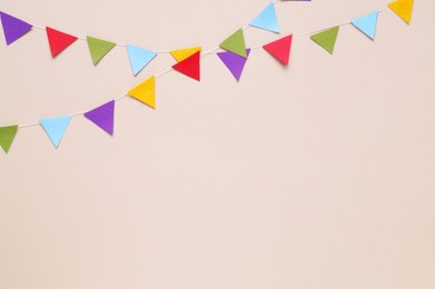 Colorful bunting flags on beige background, flat lay. Space for text