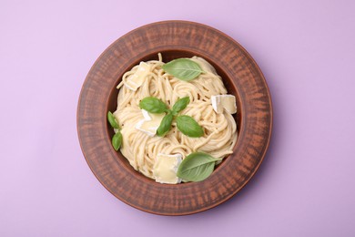 Photo of Delicious pasta with brie cheese and basil leaves on violet background, top view