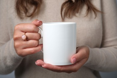 Photo of Woman holding white mug, closeup. Mockup for design