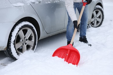 Man removing snow with shovel near car outdoors, closeup