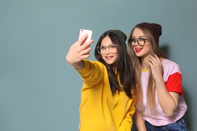 Photo of Attractive young women taking selfie on grey background