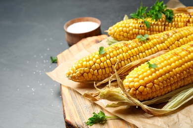 Photo of Composition with tasty grilled corn on black table