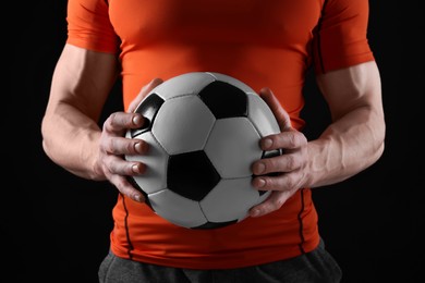 Photo of Athletic man with soccer ball on black background, closeup