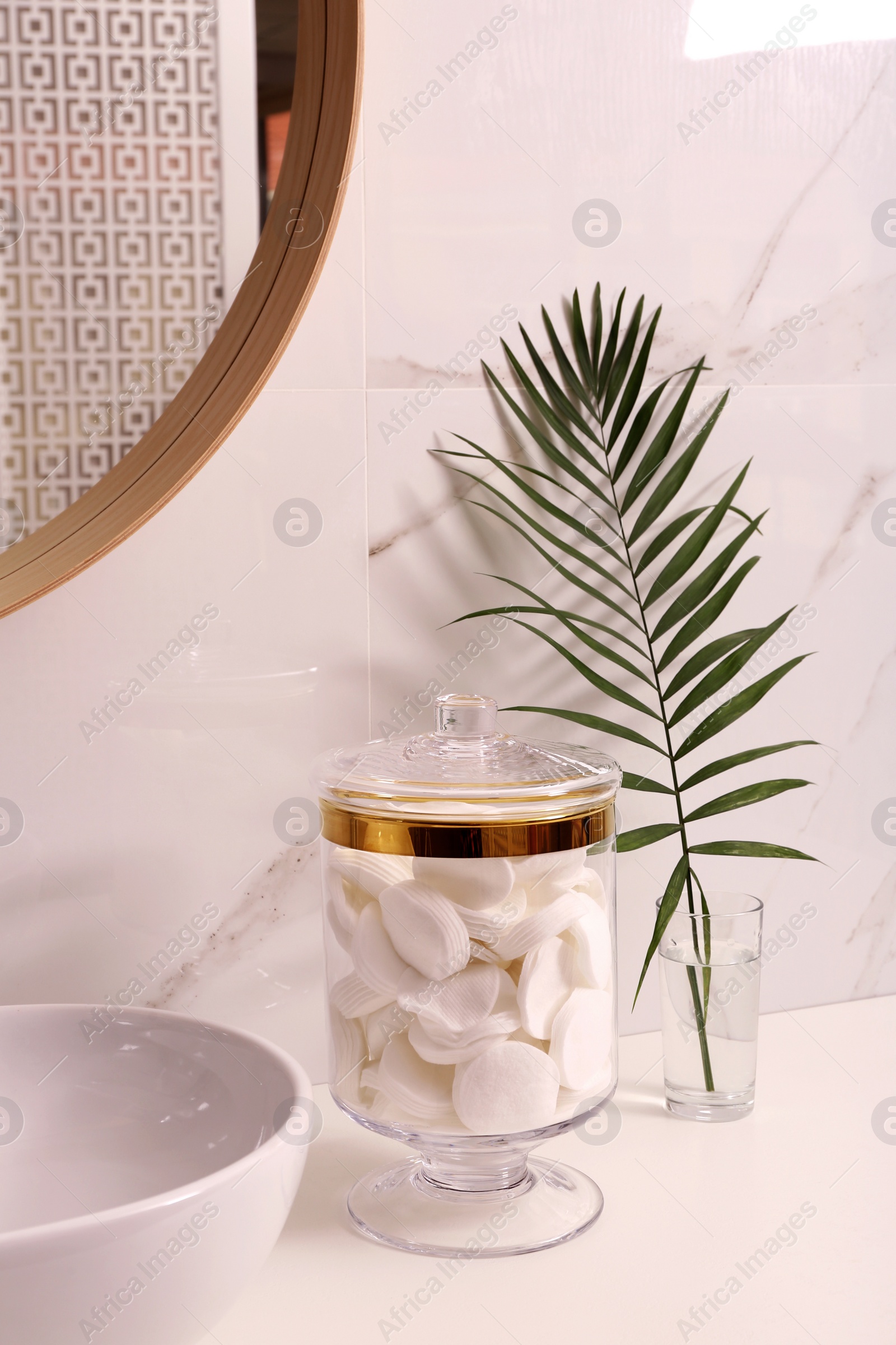 Photo of Glass jar with cotton pads on table in bathroom