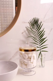 Glass jar with cotton pads on table in bathroom