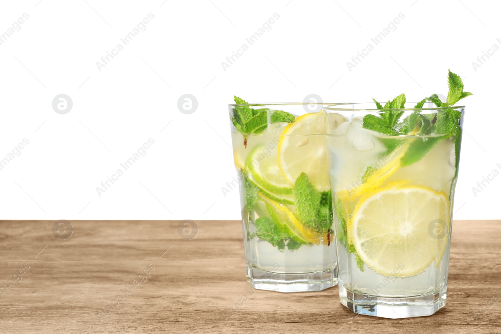 Photo of Glasses of refreshing drink with citrus slices and mint on wooden table against white background