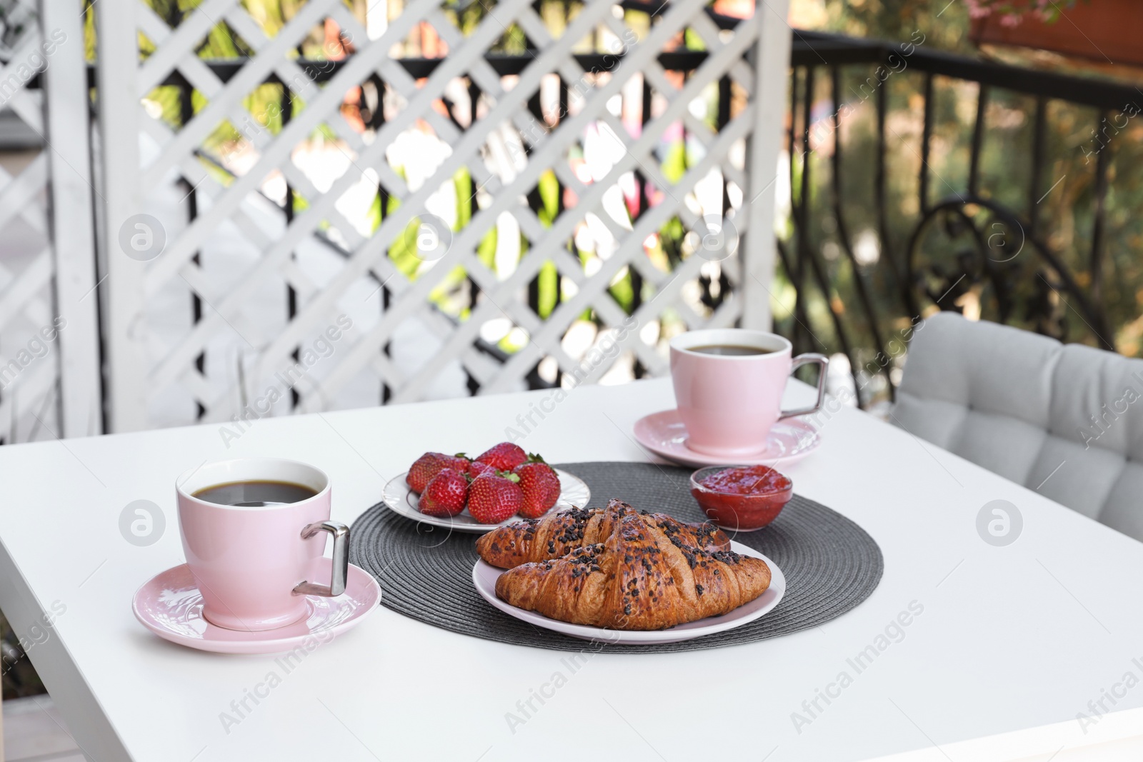 Photo of Outdoor breakfast with tea and croissants on white table on terrace