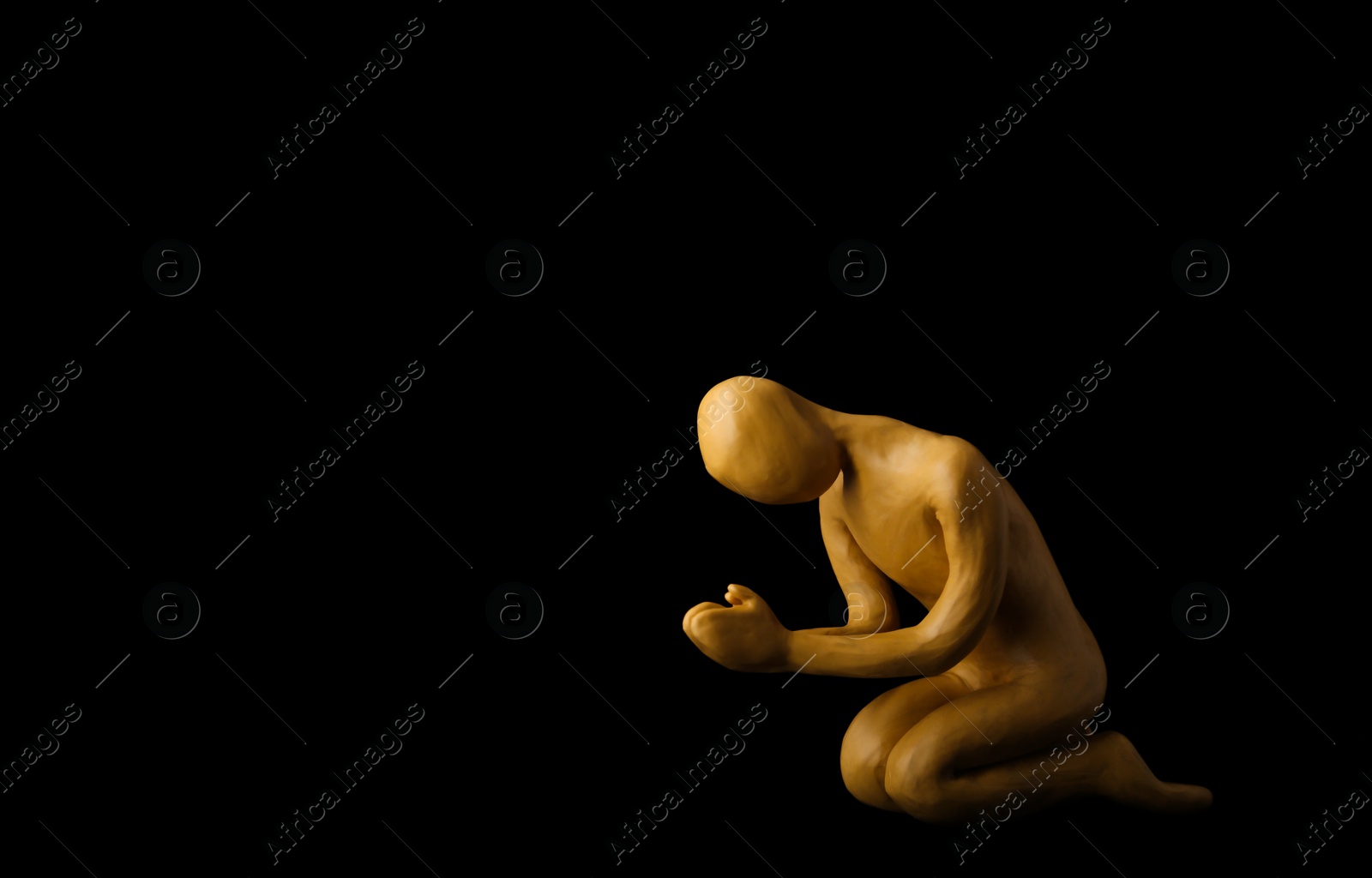Photo of Plasticine figure of praying human on black background. Space for text