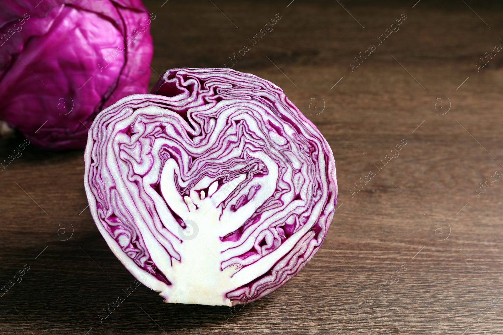 Photo of Half of fresh red cabbage on wooden table, closeup