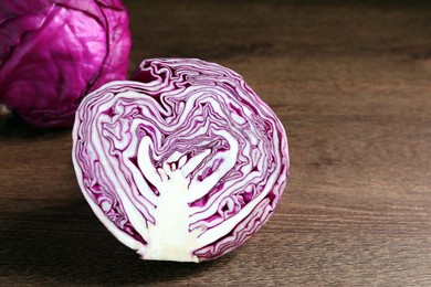 Photo of Half of fresh red cabbage on wooden table, closeup