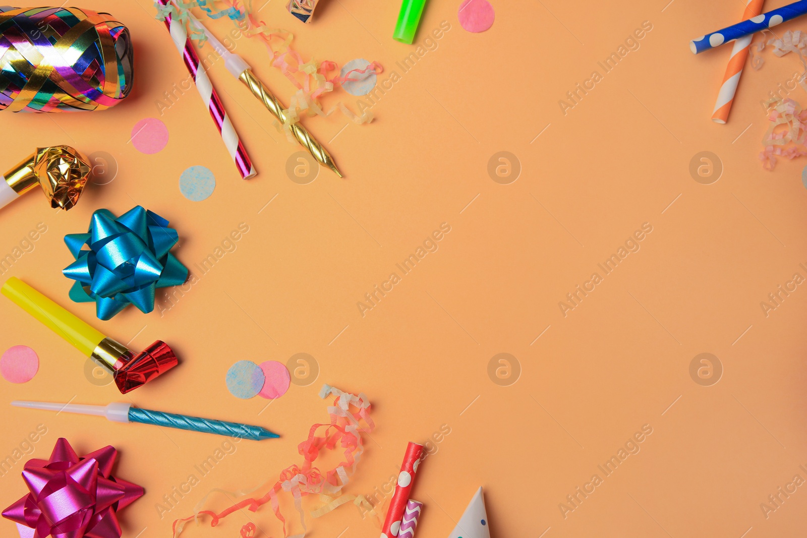 Photo of Party blowers, streamers and other festive decor on coral background, flat lay. Space for text