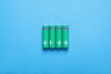 New AA size batteries on light blue background, flat lay