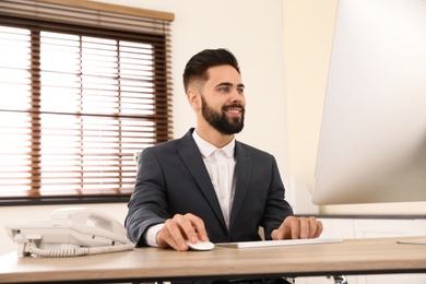 Photo of Handsome businessman working with computer at table in office