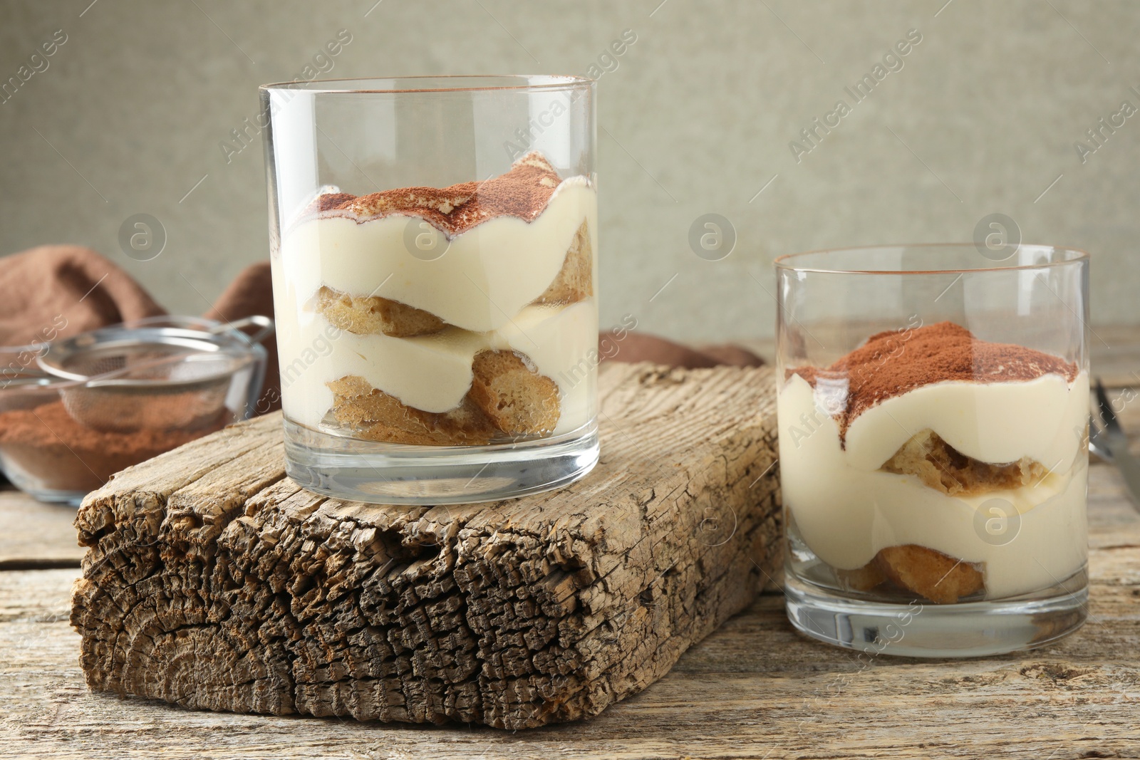 Photo of Delicious tiramisu in glasses on wooden table